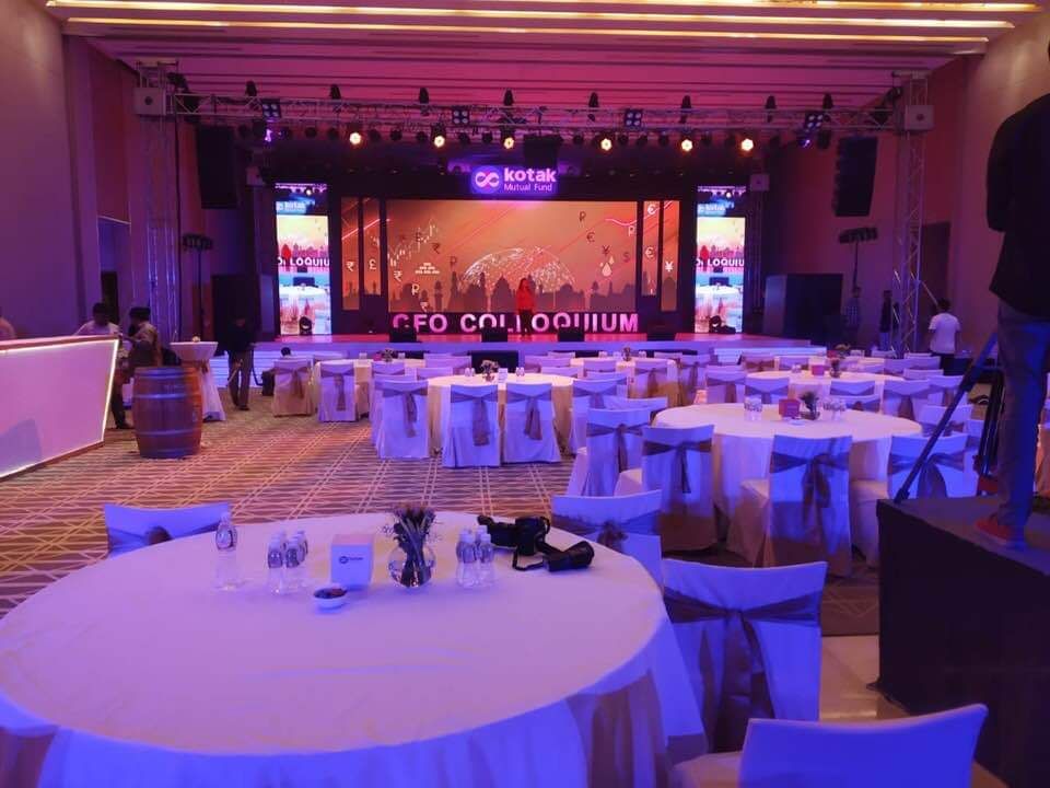 Hotel ballroom set for a conference, with an LED stage and round tables