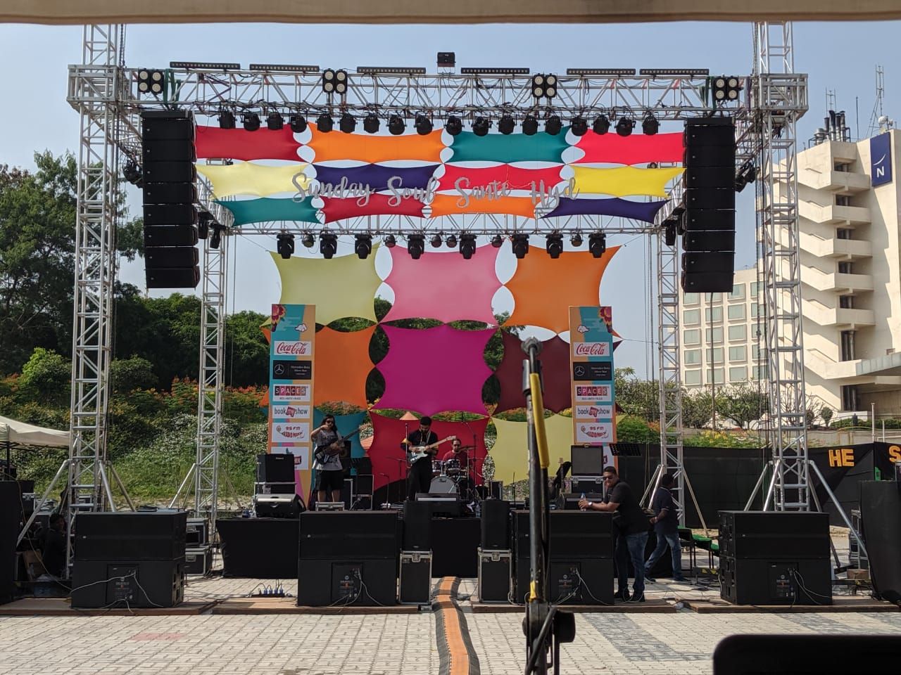 Outdoor truss stage with line-array speakers and a printed backdrop