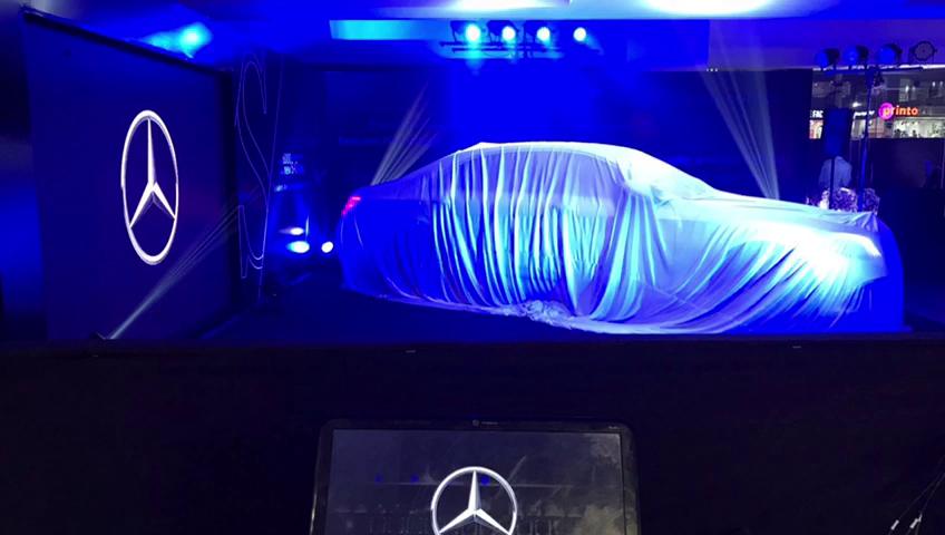 A covered car under blue light before a reveal